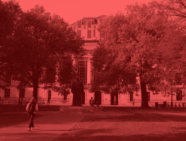 A student walks on a college campus, but the image is entirely red and black 